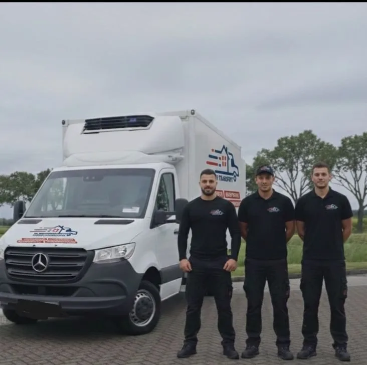 Drei Hami-Mitarbeiter in schwarzen Poloshirts vor dem geöffneten Kofferwagen, frontal, kein Posieren